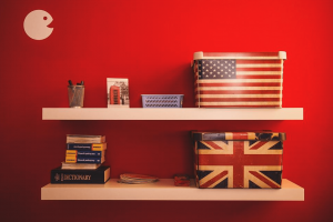 two bookshelves on a red wall with stationery, books and a union jack box